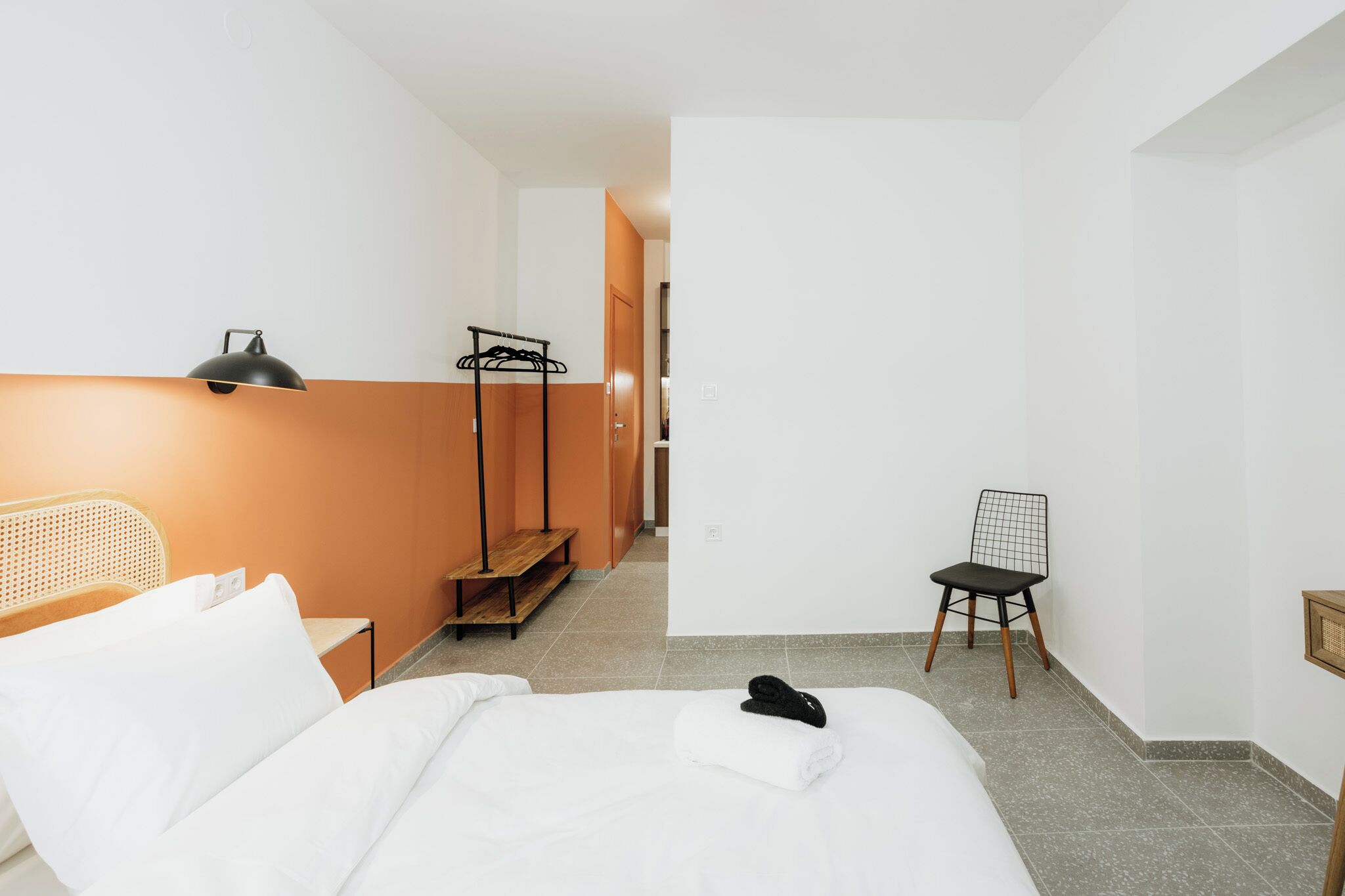 Ein Hotelzimmer mit einem Bett, einem Sessel, einer Lampe und einem Handtuch auf dem Bett.