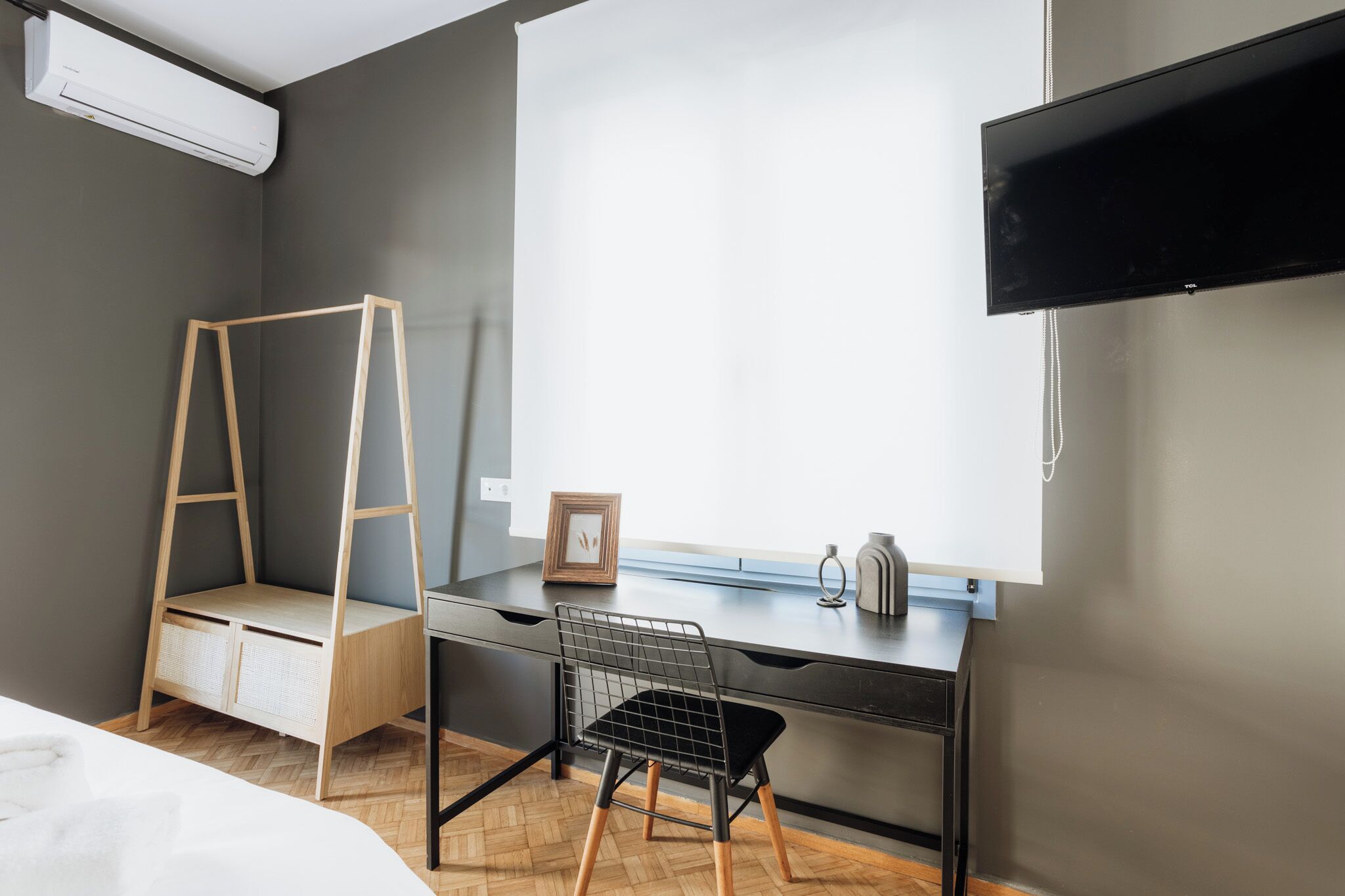 A modern bedroom with a desk, a chair, a ladder, a bed, and a TV.