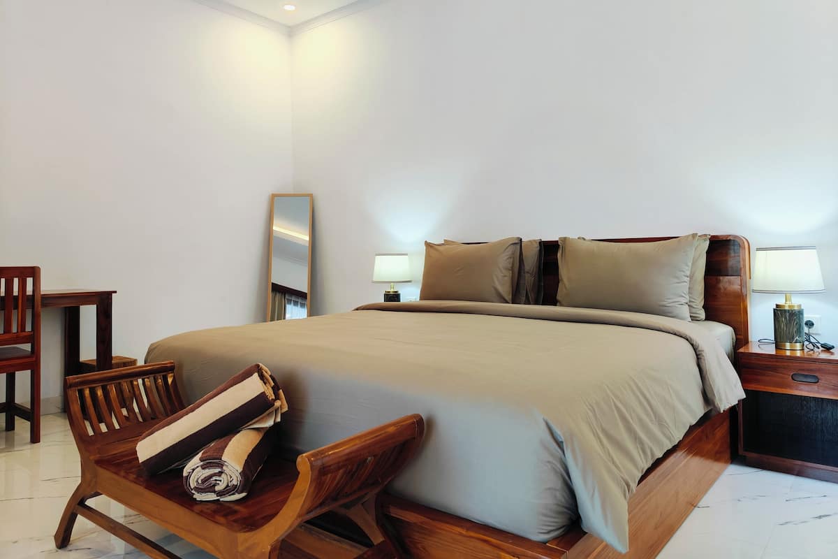 Ein ordentlich eingerichtetes Hotelzimmer mit einem großen Bett, Holzmöbeln und einem Nachttisch mit Lampe.