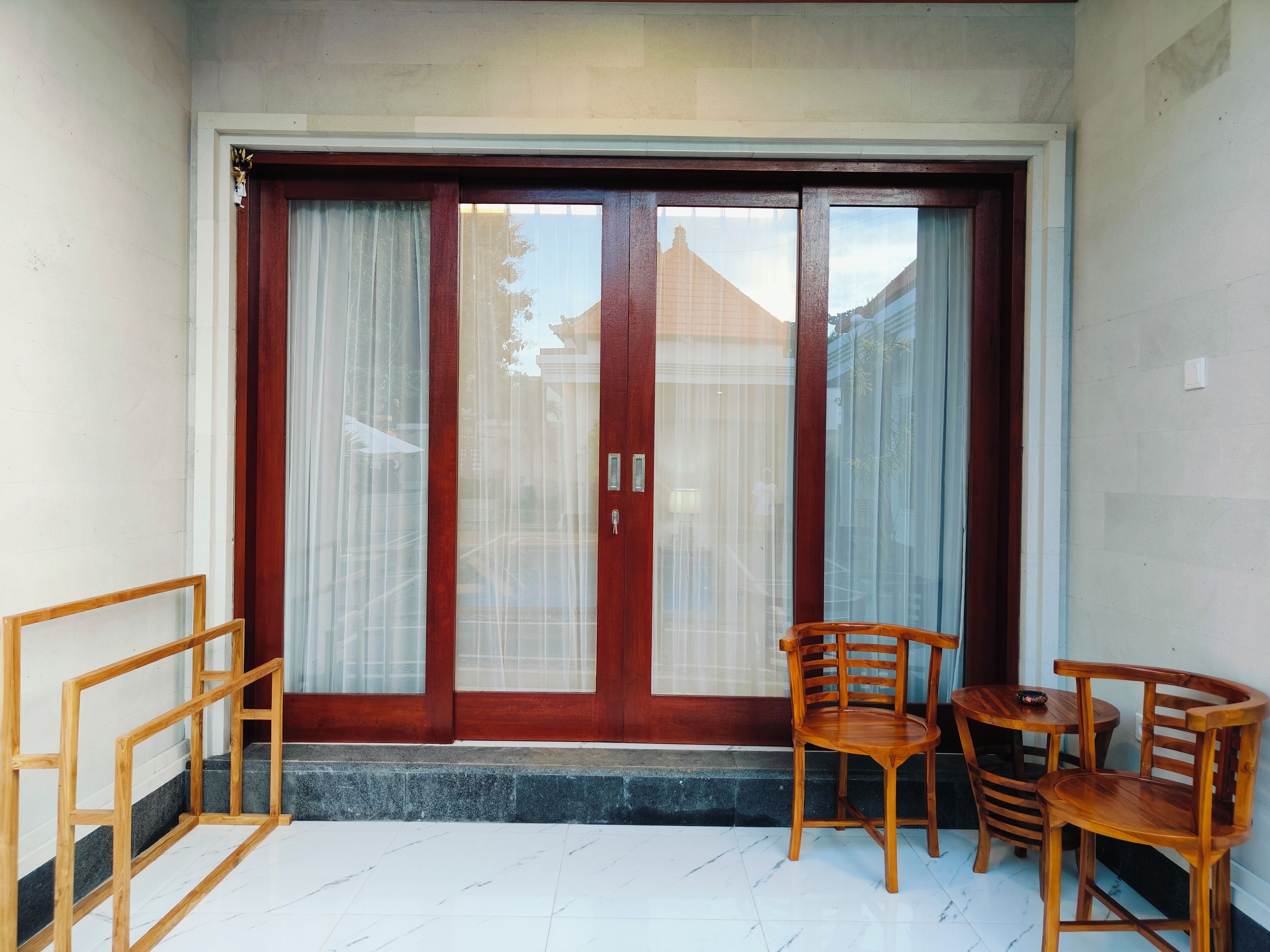 A room with a sliding glass door, a wooden bench, and a small table.