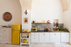 A kitchen with white cabinets, a yellow refrigerator, a microwave, and a tiled backsplash. - Masseria Pezza La Spina (Ostuni)