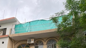 A two-story building with a balcony, air conditioning units, and a green tree in front. - Luxury Guest House (Islamabad)
