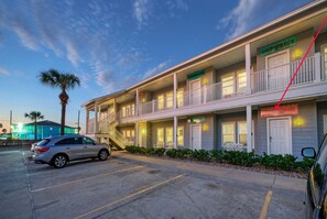 A motel with multiple floors, balconies, and a parking lot. - Sleeps 10 | Two Condos. Pet-Friendly + Beach access (Port Aransas)