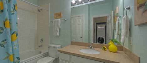 A bathroom with a bathtub, toilet, sink, and a mirror with lights.