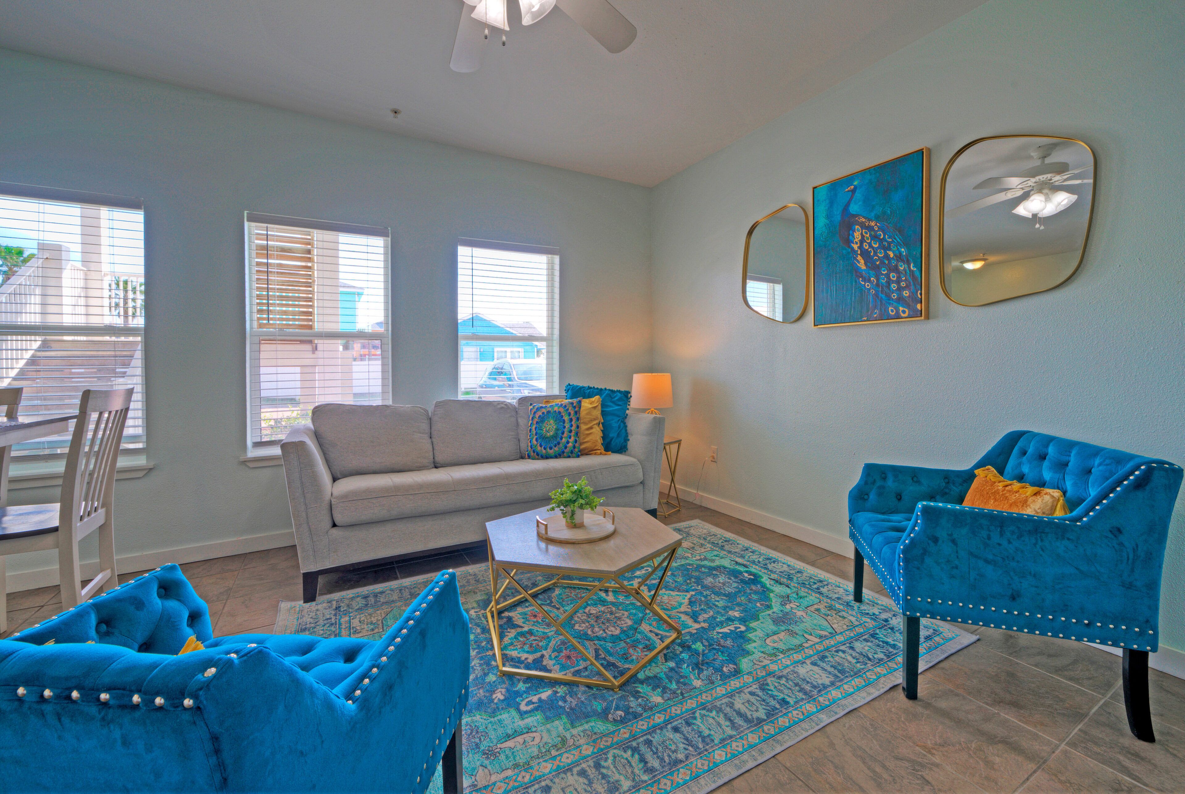 A living room with a grey sofa, blue armchairs, a coffee table, and a patterned rug.