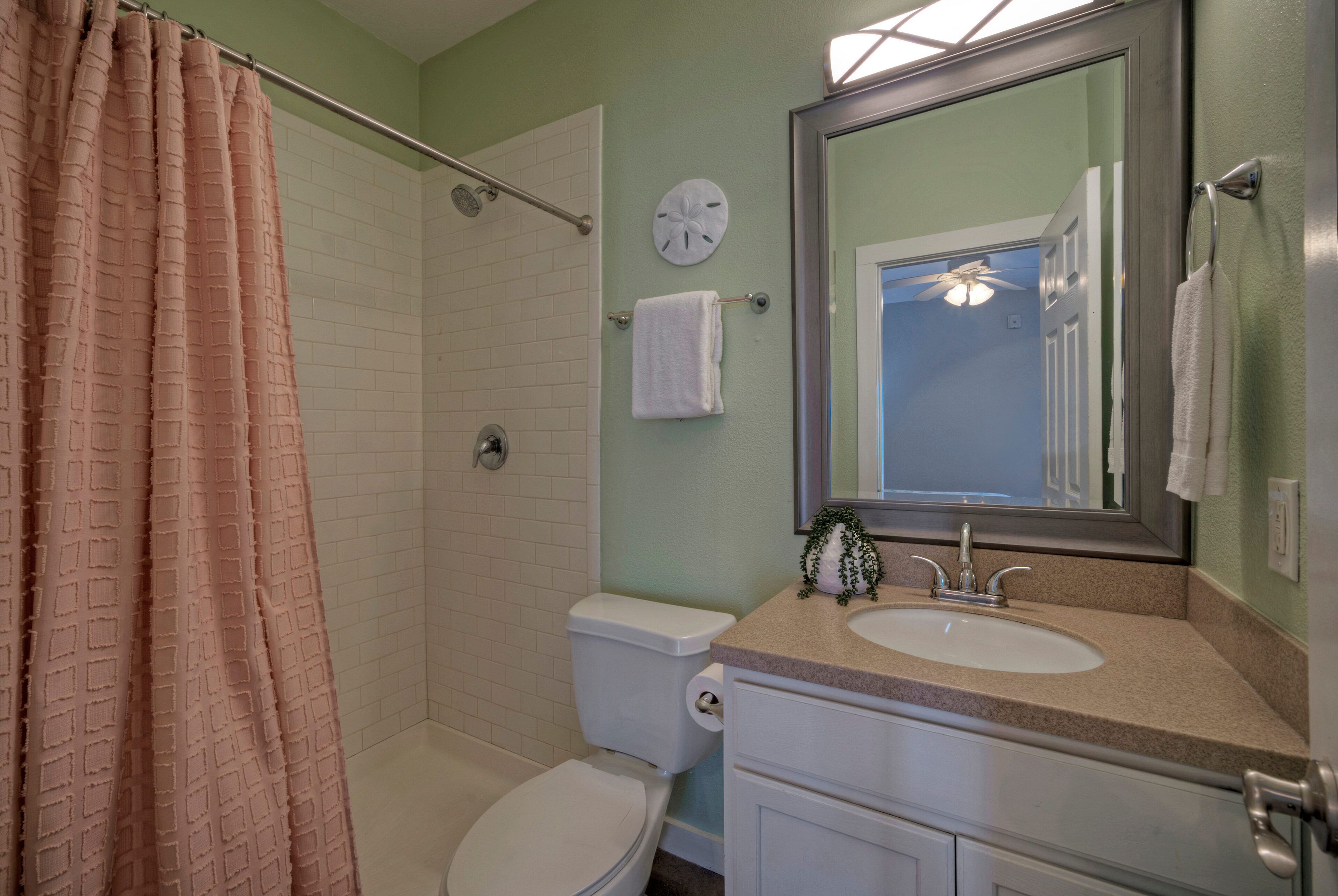 Une salle de bain équipée d’une douche, de toilettes, d’un lavabo et d’un miroir.