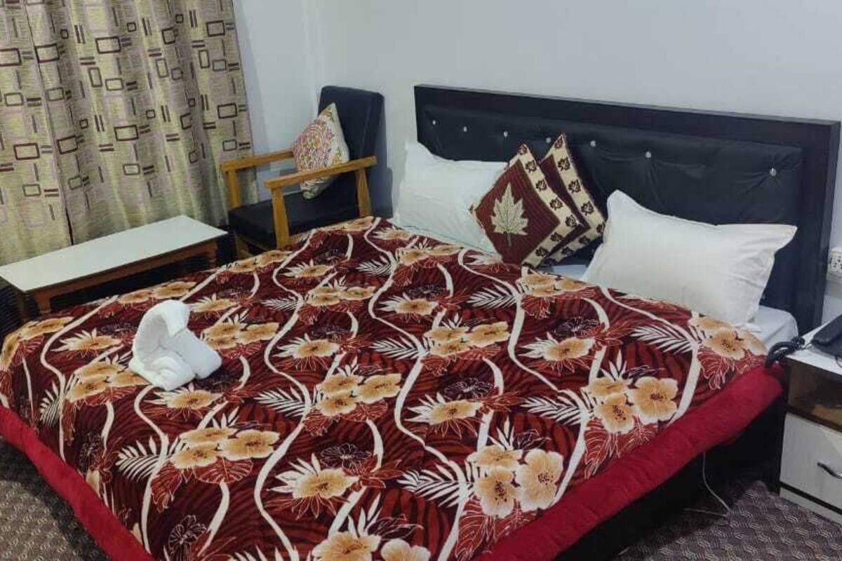 A hotel room with a bed, a chair, a desk, and a nightstand.