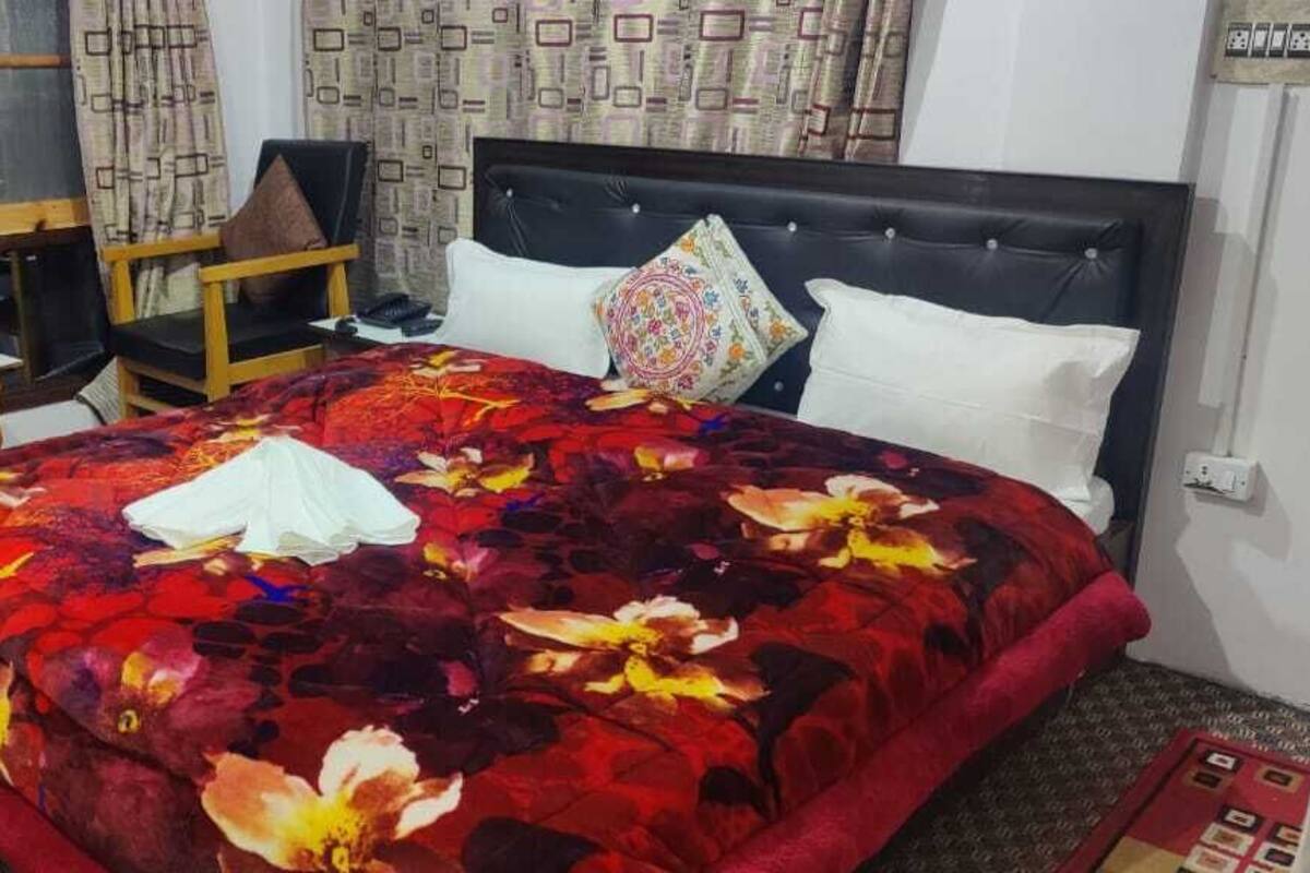 A hotel room with a large bed, a wooden nightstand, a chair, and a desk.