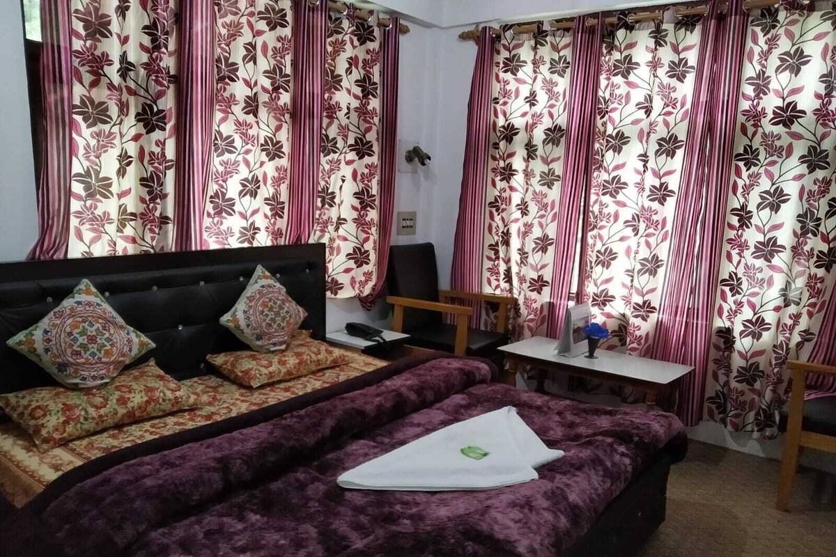 A bedroom with a large bed, a desk, and curtains with a floral pattern.