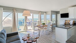 Una cocina moderna con comedor, ventanas amplias y vista al océano.