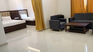 A modern hotel room with a bed, two armchairs, a sofa, a coffee table, and a TV. - Hotel Ganga Greens (Lucknow)