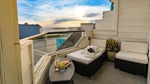 Ein Balkon mit Meerblick, ein Esstisch gedeckt mit Speisen und zwei Sofas.