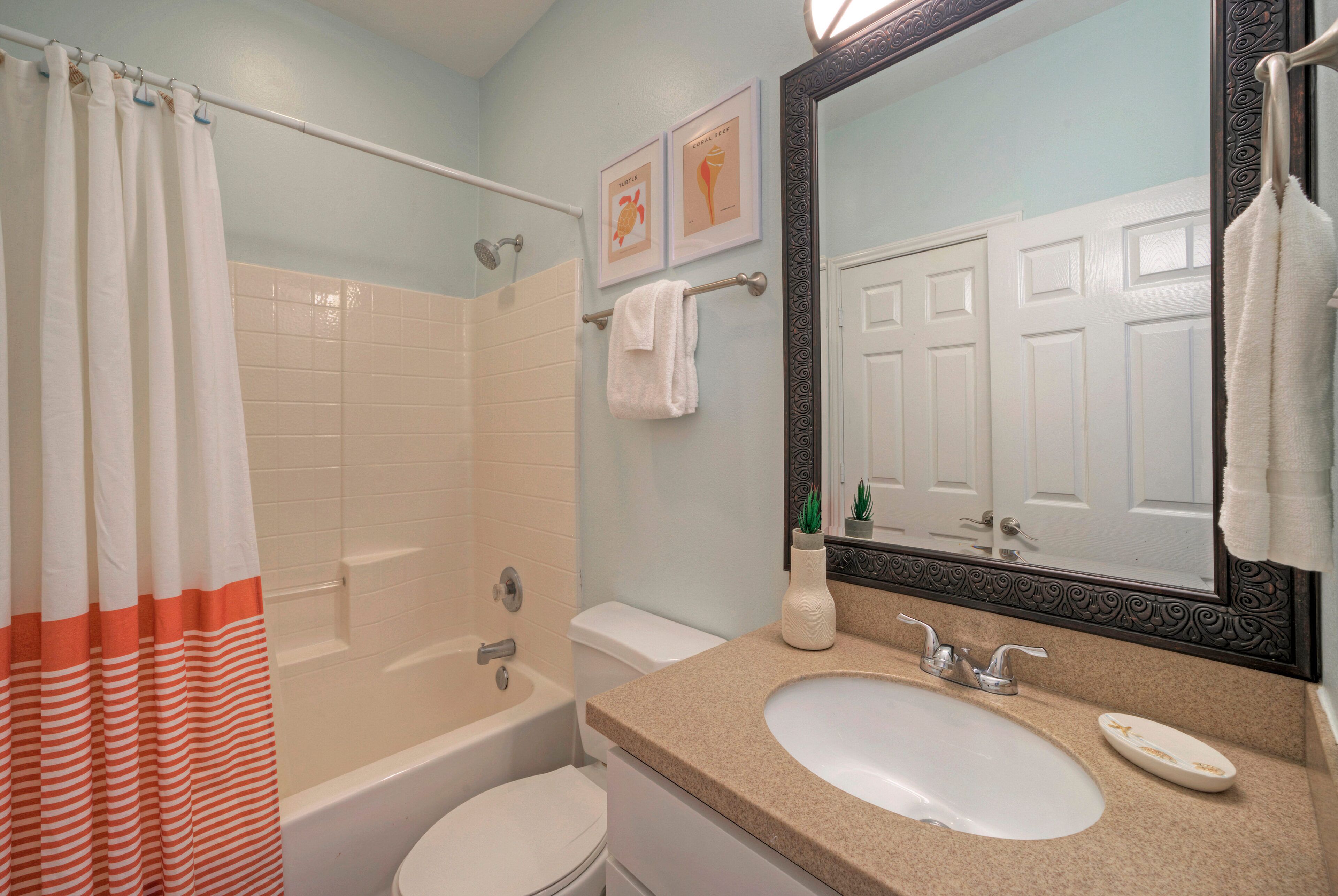 A bathroom with a bathtub, toilet, sink, and a large mirror.