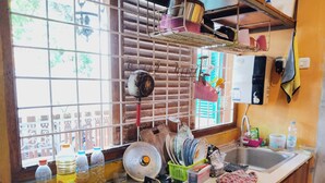 A kitchen with a gas stove, sink, and various kitchen items. - Rumah Betawi Kalipasir (Jakarta)