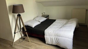 Makuuhuone, jossa on sänky, lamppu, yöpöytä ja patteri.