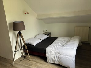 A bedroom with a bed, a lamp, a nightstand, and a radiator.