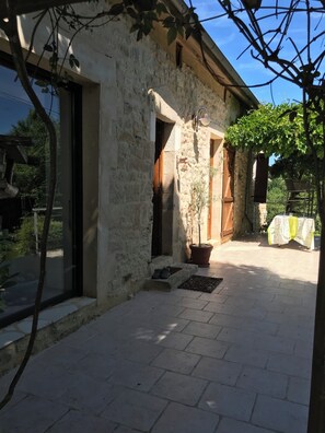 A stone building with a door, a potted plant, and a table with a cloth.