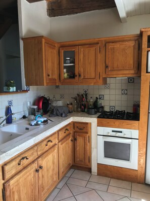 A kitchen with wooden cabinets, a white countertop, a stove, and a sink.