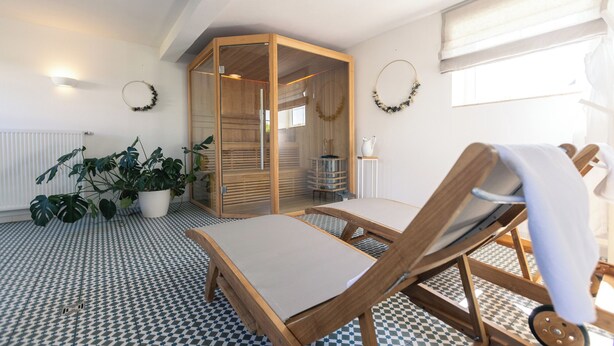 A room with a checkered floor, a wooden cabinet, a lounge chair, and potted plants.