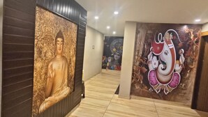 Un couloir orné d’une statue de Bouddha et d’une fresque représentant Ganesha, qui mène à une pièce dont le sol est recouvert de carreaux.