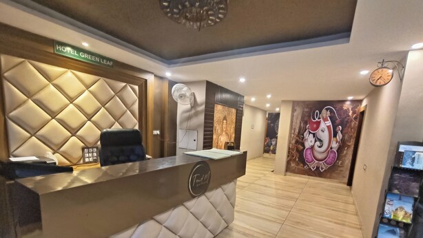 Un espace d’accueil d’hôtel au design moderne, comprenant un comptoir d’accueil, un coin salon et un mur orné d’une fresque.