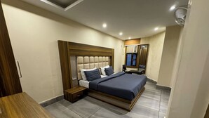 Une chambre moderne avec un grand lit, une table de chevet en bois, une petite table et un ventilateur de plafond.