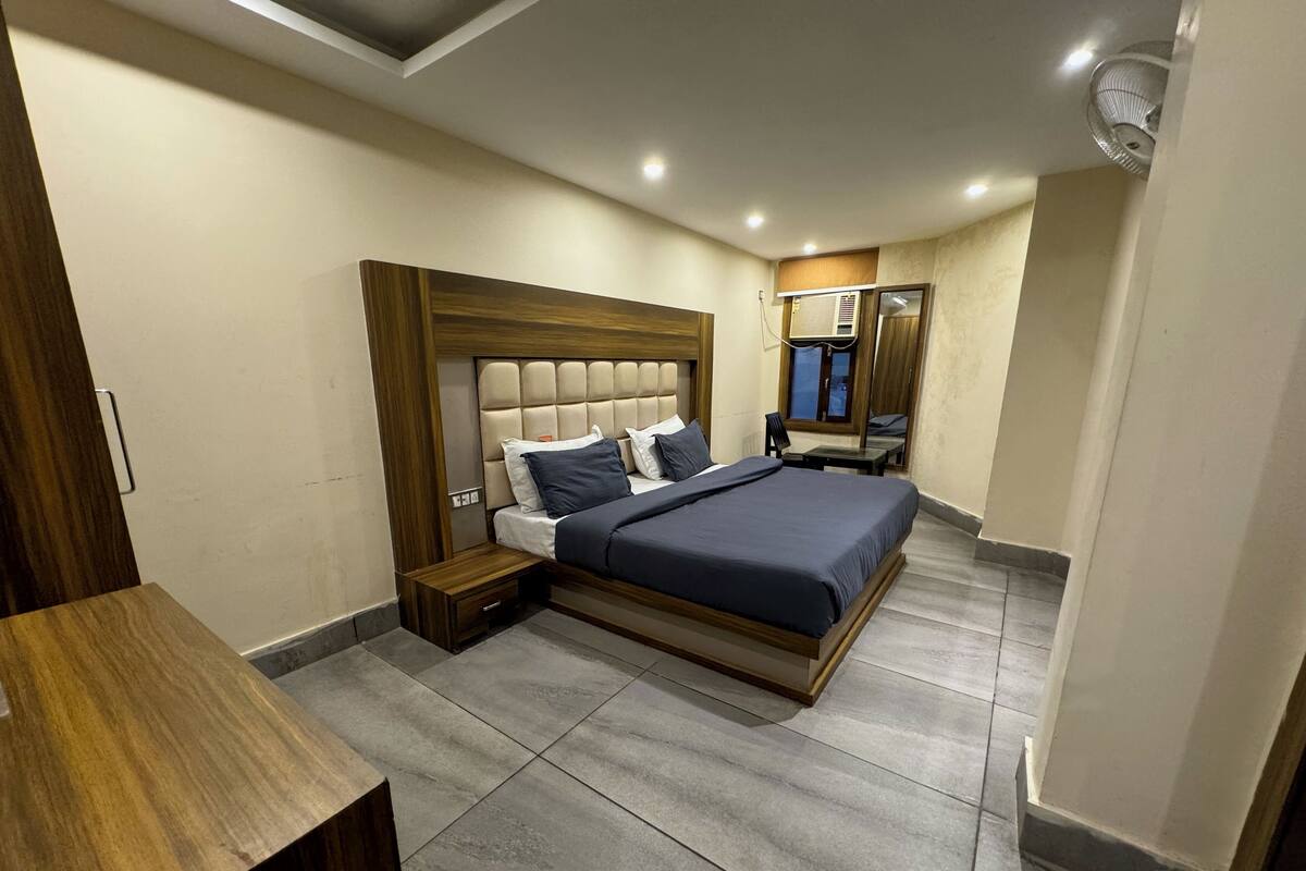 Een moderne slaapkamer met een groot bed, een houten nachtkastje, een klein tafeltje en een plafondventilator.