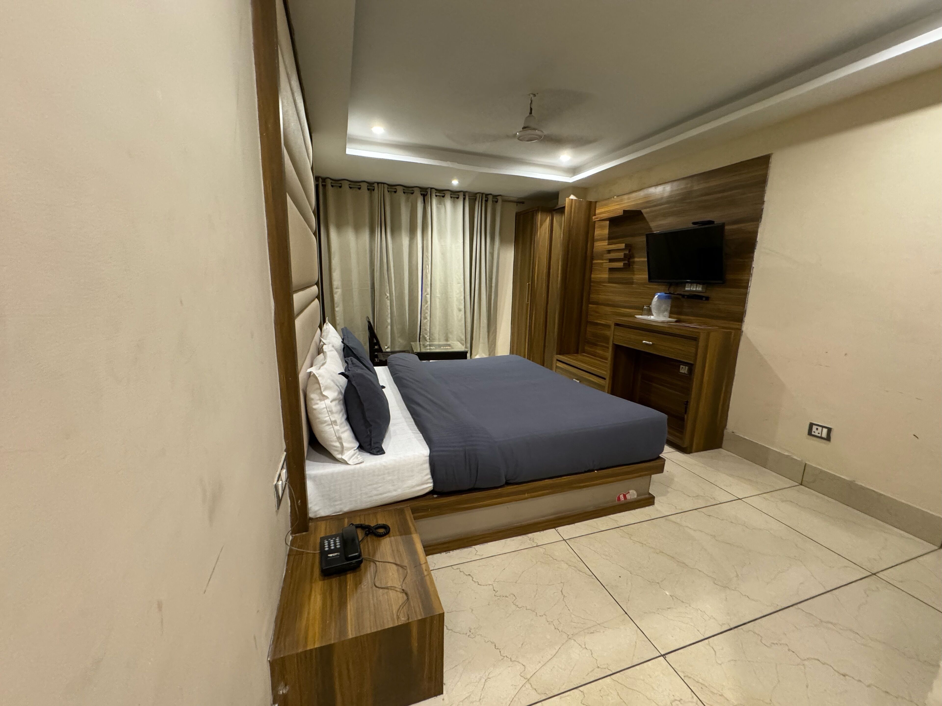 Una habitación de hotel con cama, escritorio, televisor y armario de madera.