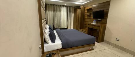 Una habitación de hotel con cama, escritorio, televisor y armario de madera.