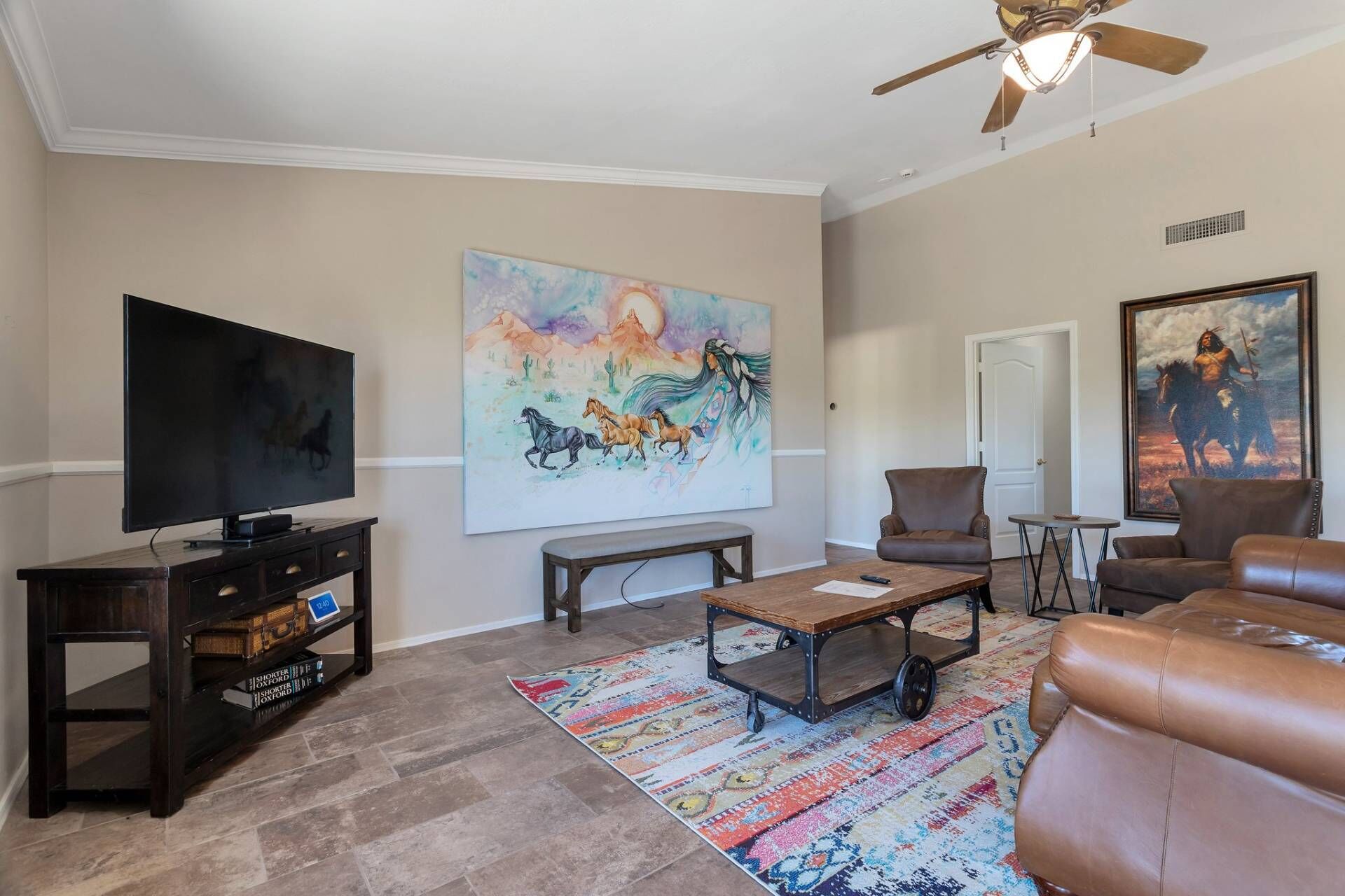 A living room with a television, a painting, a sofa, and a coffee table.