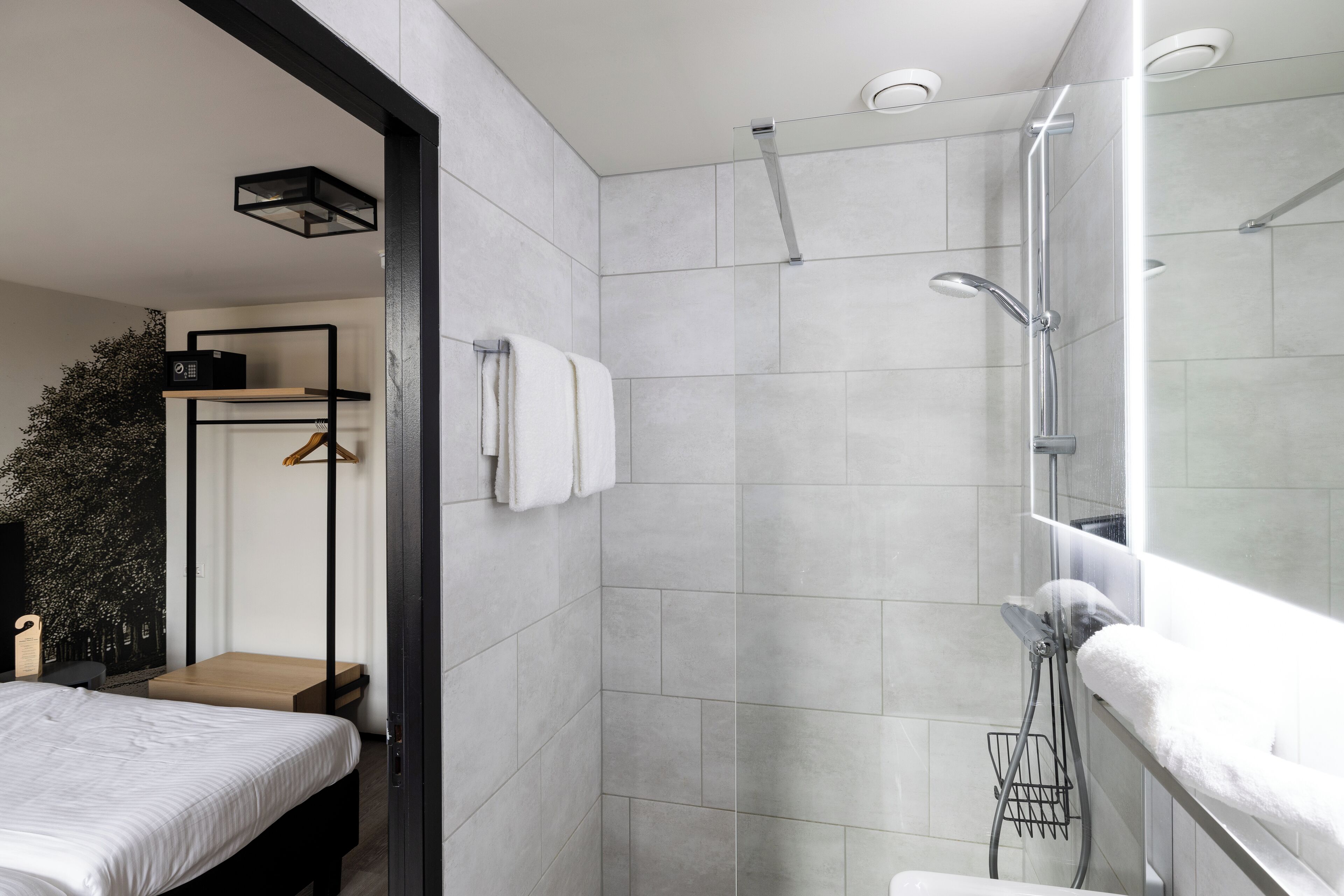 Een moderne badkamer met een douche, toilet en een bed.
