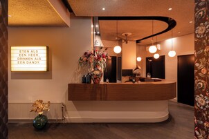 A reception area with a wooden counter, a floral arrangement, and a sign with text.