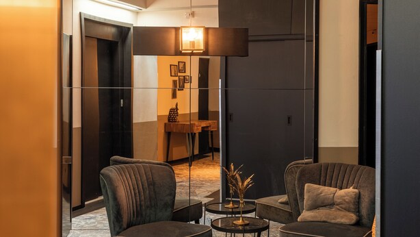 A modern living room with two armchairs, a coffee table, and a unique circular ceiling light fixture. - Boutique Hotel de Statie (Valkenswaard)