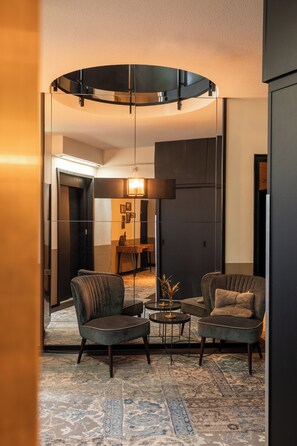 Un salon moderne avec deux fauteuils, une table basse et un luminaire de plafond circulaire original.