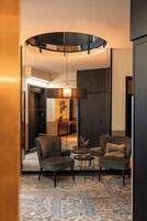 A modern living room with two armchairs, a coffee table, and a unique circular ceiling light fixture.