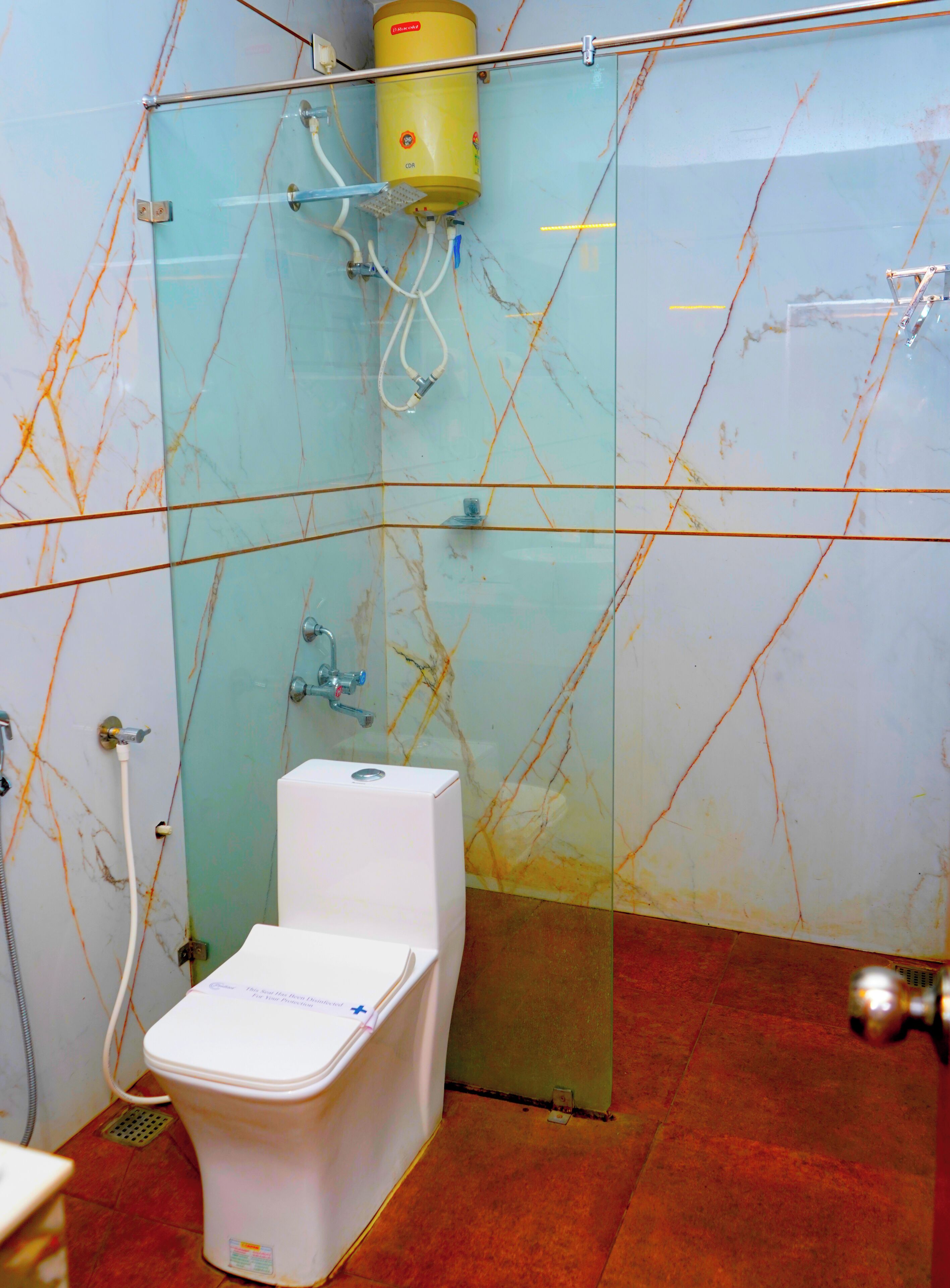 A bathroom with a glass shower enclosure, a white toilet, and a visible water heater.
