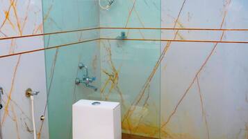 A bathroom with a glass shower enclosure, a white toilet, and a visible water heater.
