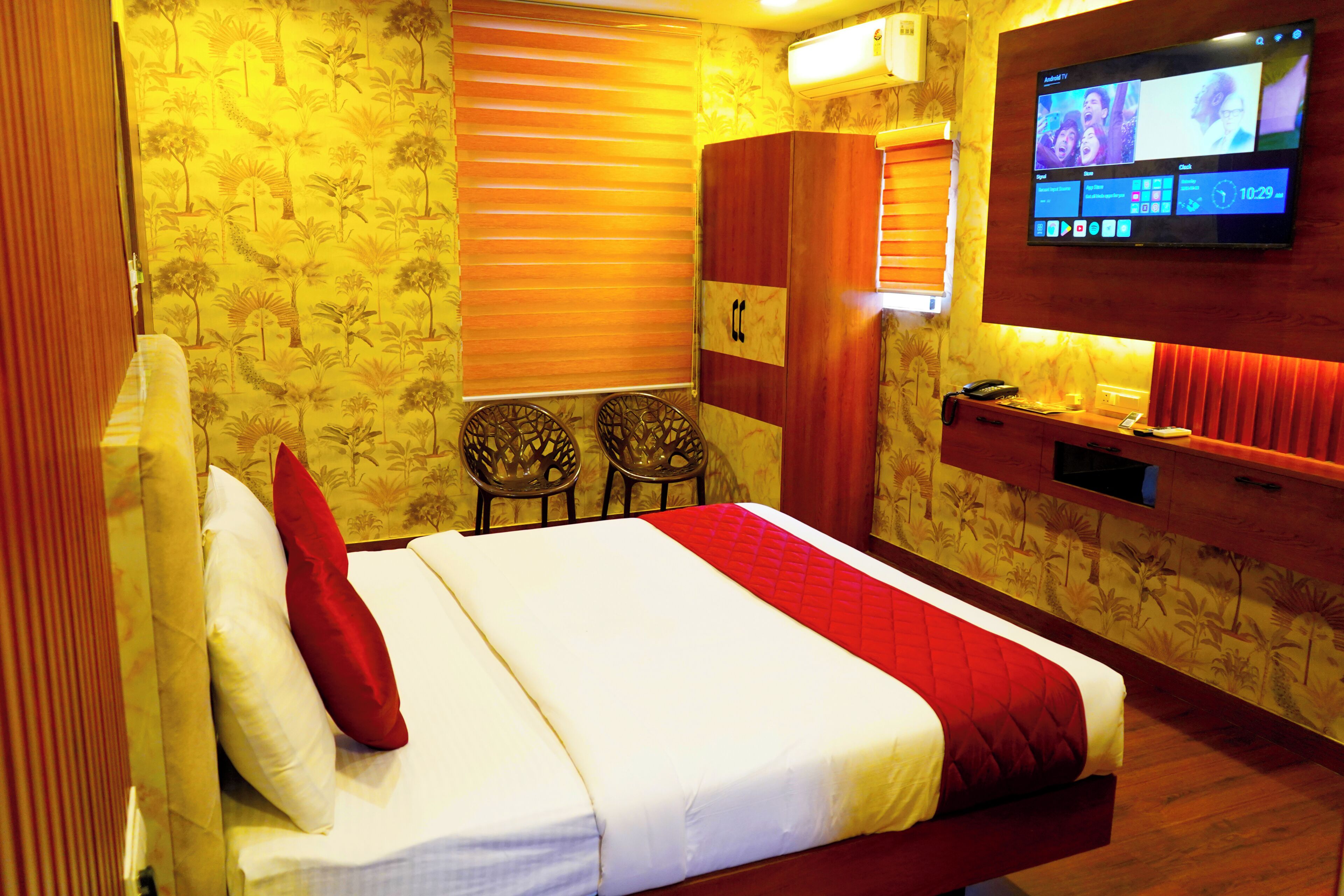 Habitación de hotel con cama, televisión montada en la pared, escritorio con teléfono y una silla.