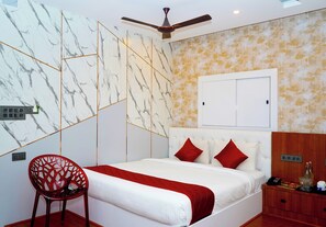 A bedroom with a bed, a chair, a wardrobe, and a ceiling fan. - Winners Hill Resort Walayar by Arcadia (Coimbatore)