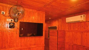 A wooden room with a mounted fan, a television, and an air conditioning unit. - WINNERS HILL RESORTS (Coimbatore)