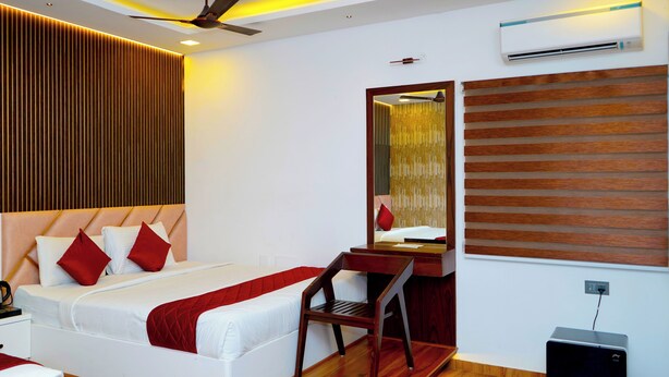 A modern hotel room with a bed, a desk, a chair, an air conditioning unit, and a ceiling fan. - WINNERS HILL RESORTS (Coimbatore)