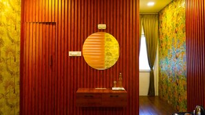 A room with a wooden panel wall, a round mirror, and a wooden cabinet with drawers. - WINNERS HILL RESORTS (Coimbatore)