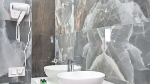 Casa de banho com lavatório branco, espelho e secador de cabelo na parede.