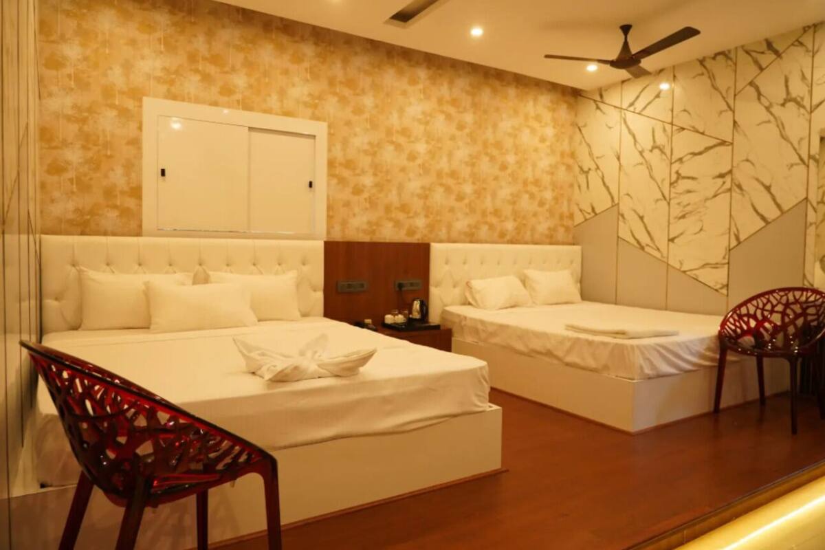 A hotel room with two beds, a ceiling fan, a mirror, and a red chair.