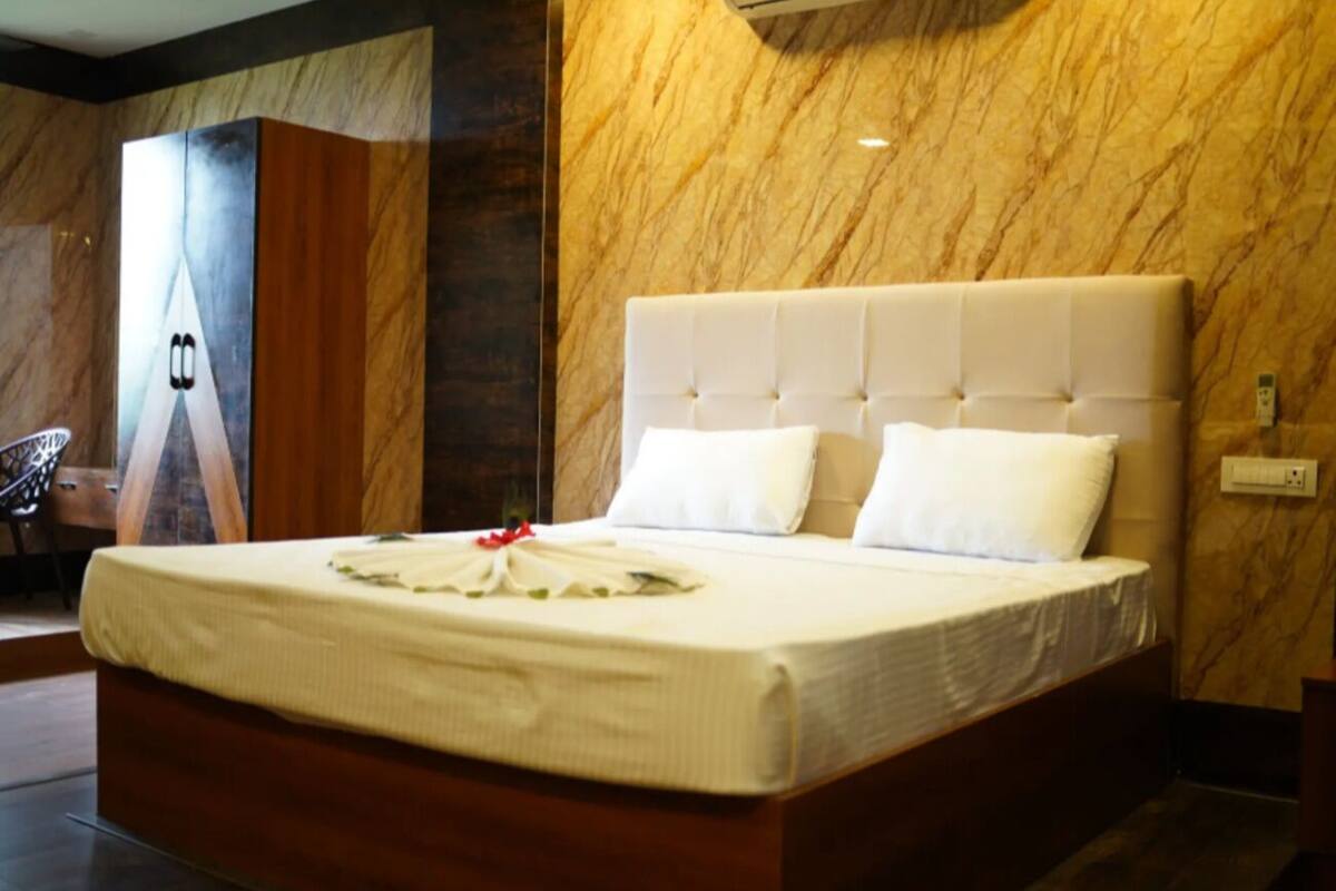 A large bed with a tufted headboard, white bedding, and a decorative arrangement on the bed.