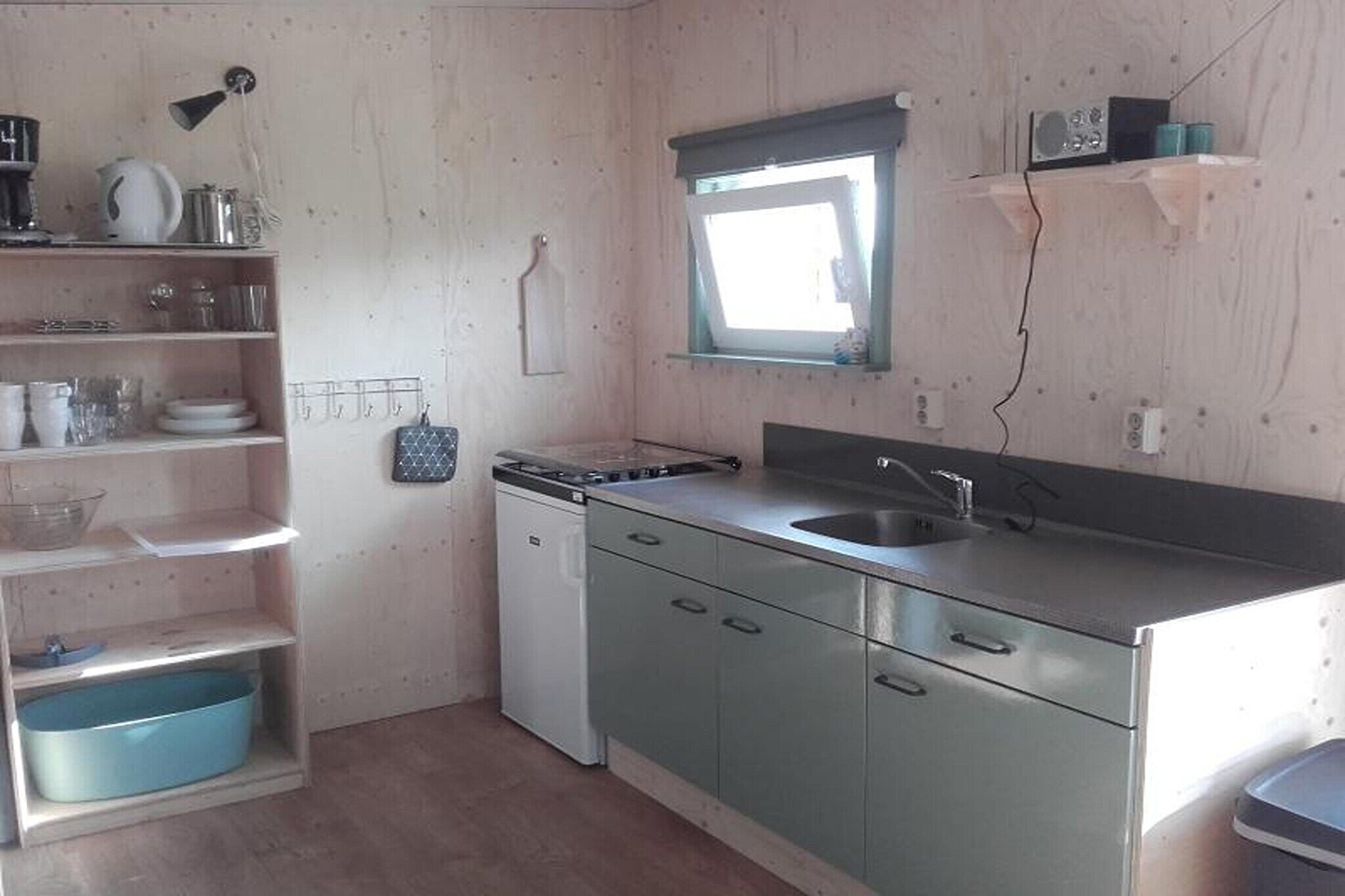 Una cucina compatta con lavello, una lavastoviglie piccola e una finestra sopra il lavello.