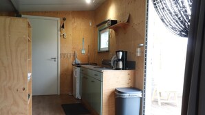 Ett kompakt kök med träskåp, en kaffebryggare och en papperskorg.