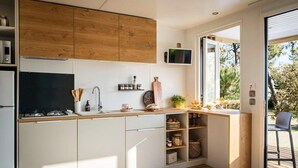 Una cocina moderna con armarios de madera, estufa integrada y un amplio ventanal que proporciona luz natural.