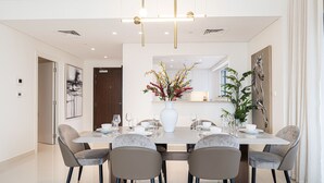 A modern dining area with a rectangular table, six chairs, and a central vase with flowers. - 3Br + Maid Close To Burj Khalifa Dubai Mall (Dubai)