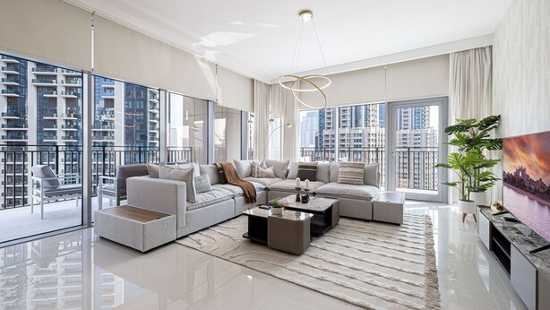 A spacious living room with a large sectional sofa, a coffee table, and a TV on a stand. There is a large window offering a view of high-rise buildings. - 3Br + Maid Close To Burj Khalifa Dubai Mall (Dubai)